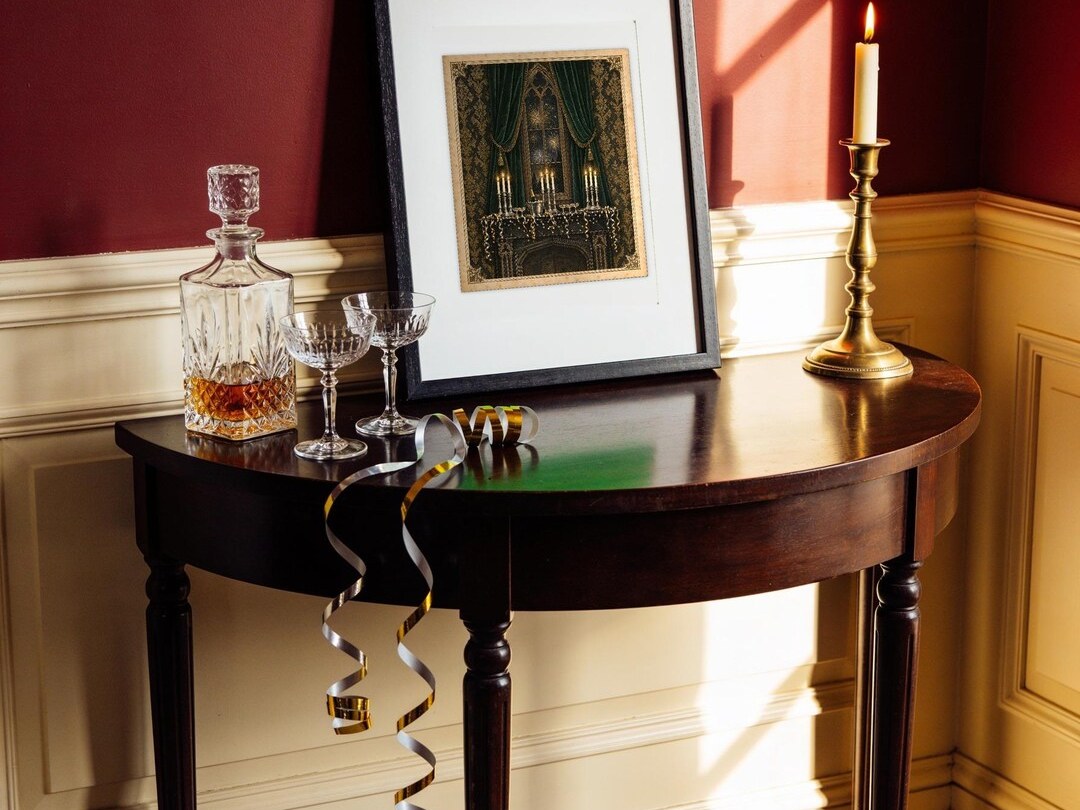 Victorian New Year's Eve print on a side table with a decanter and candle